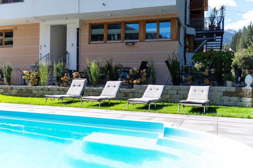 Freischwimmbad mit Liegen vor dem Hotel Enzian