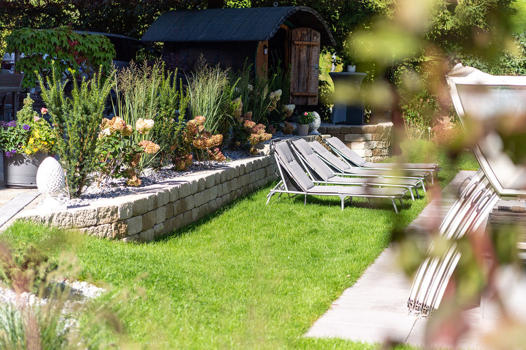 Sunbathing lawn with barrel sauna in the garden of Hotel Enzian
