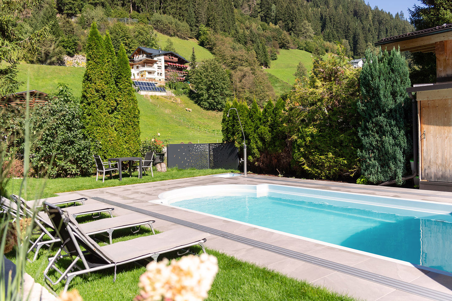 Freischwimmbad mit Liegewiese vor dem Hotel Enzian