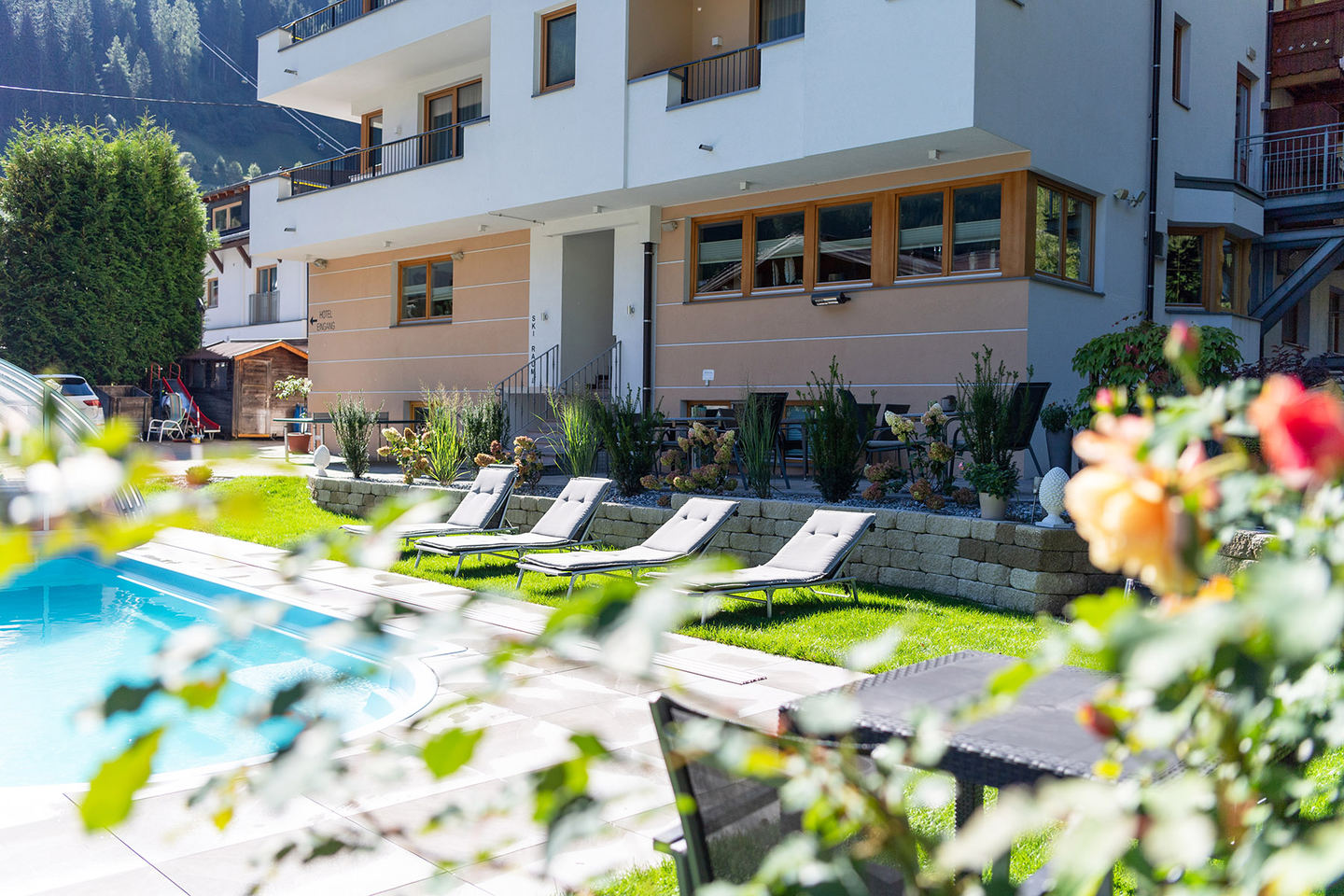 Freibad mit Liegen und Rosen im Garten des Hotel Enzian